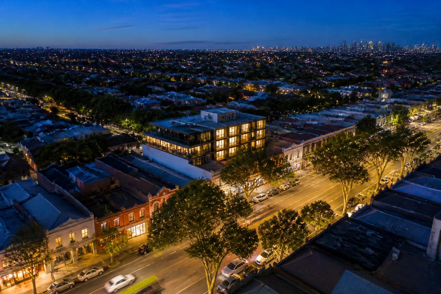 Artist impression of a mixed-use building within a Melbourne suburban retail strip at dusk